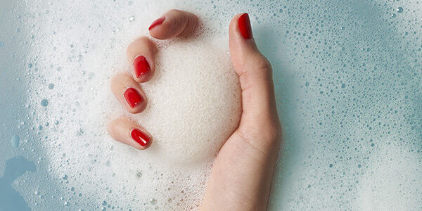 יד של אשה מחזיקה ספוג באמבטיה